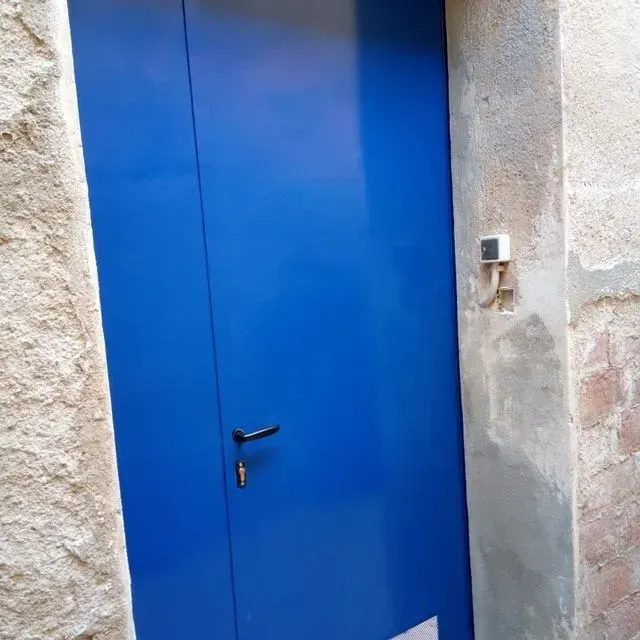Puerta azul con marco de hormigón envejecido de color claro.