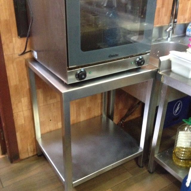 Horno de acero inoxidable sobre un estante de metal en una cocina comercial.