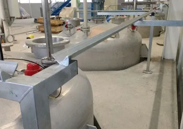 Equipo industrial en entorno fabril, con depósitos metálicos y estructuras de soporte.