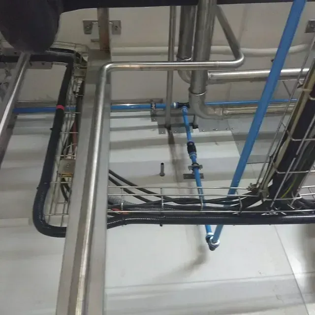 Vista aérea de tuberías y cables en un entorno industrial, incluidos conductos plateados, azules y negros.