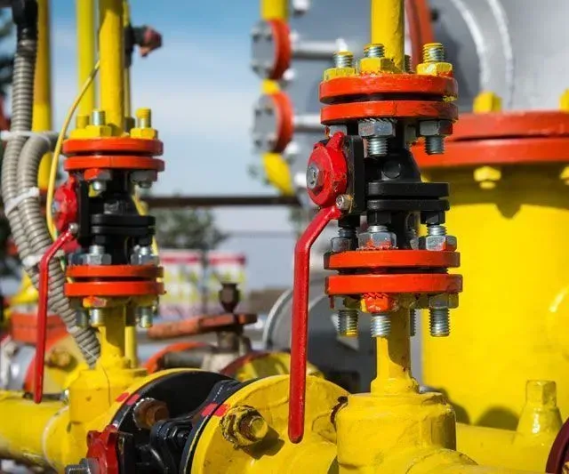 Tuberías de gas amarillas con válvulas, pernos y accesorios de color rojo y negro.