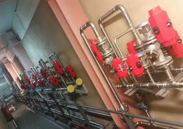 Tuberías con múltiples válvulas de manija roja montadas en una pared.