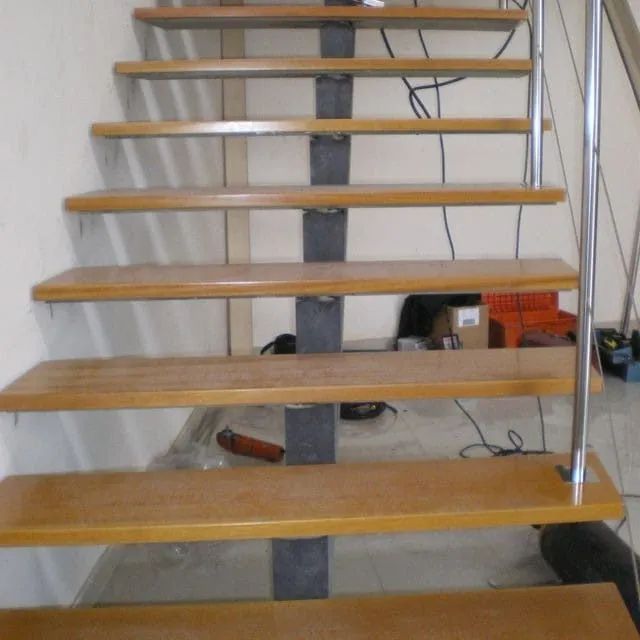 Escalera flotante de madera con apoyo central y barandilla de acero inoxidable.