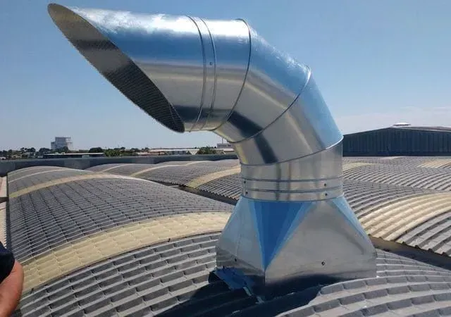 Conductos de ventilación metálicos sobre un tejado curvo, en ángulo hacia arriba.