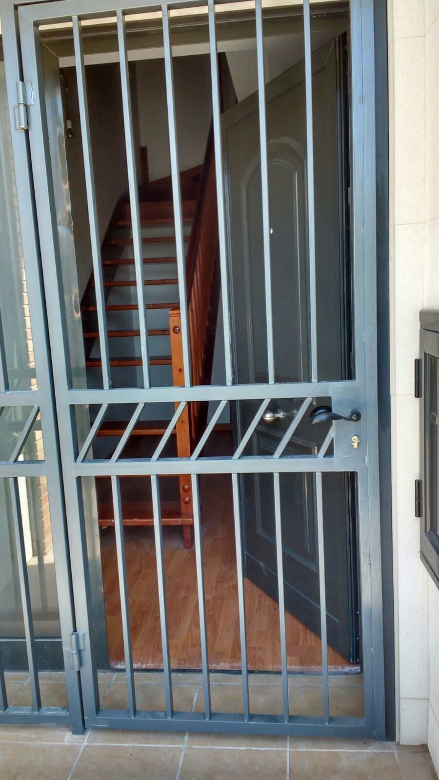 Puerta de seguridad gris frente a una puerta gris con escaleras visibles al fondo.