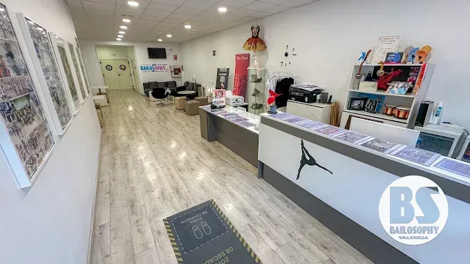 Luminoso vestíbulo de oficina con mostrador de recepción, sillas, carteles y una puerta al fondo.