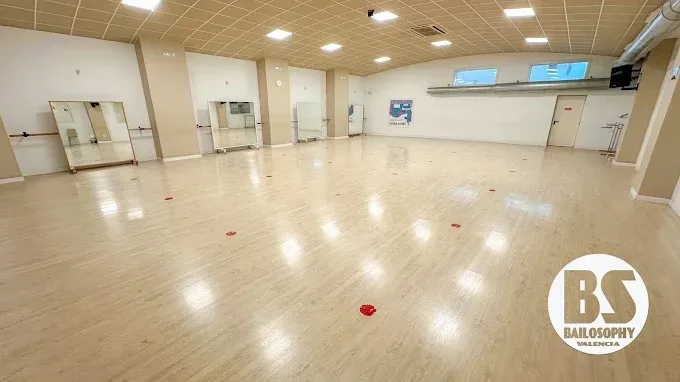 Estudio de danza luminoso y vacío, con suelo de madera, espejos y luces en el techo