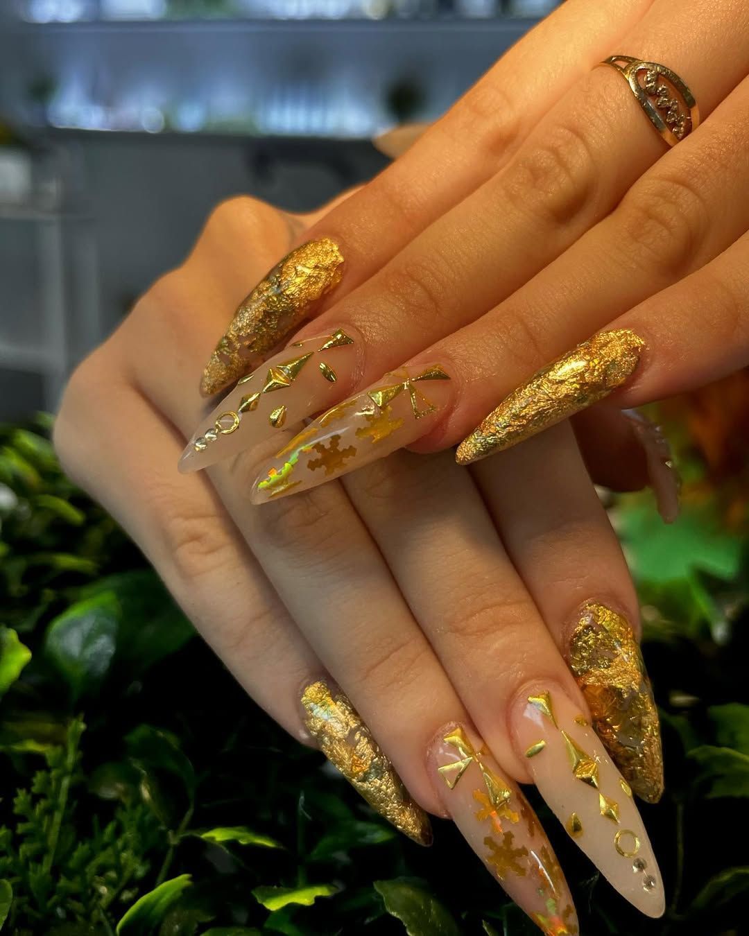 Manos con largas uñas de aguja doradas con purpurina cruzadas
