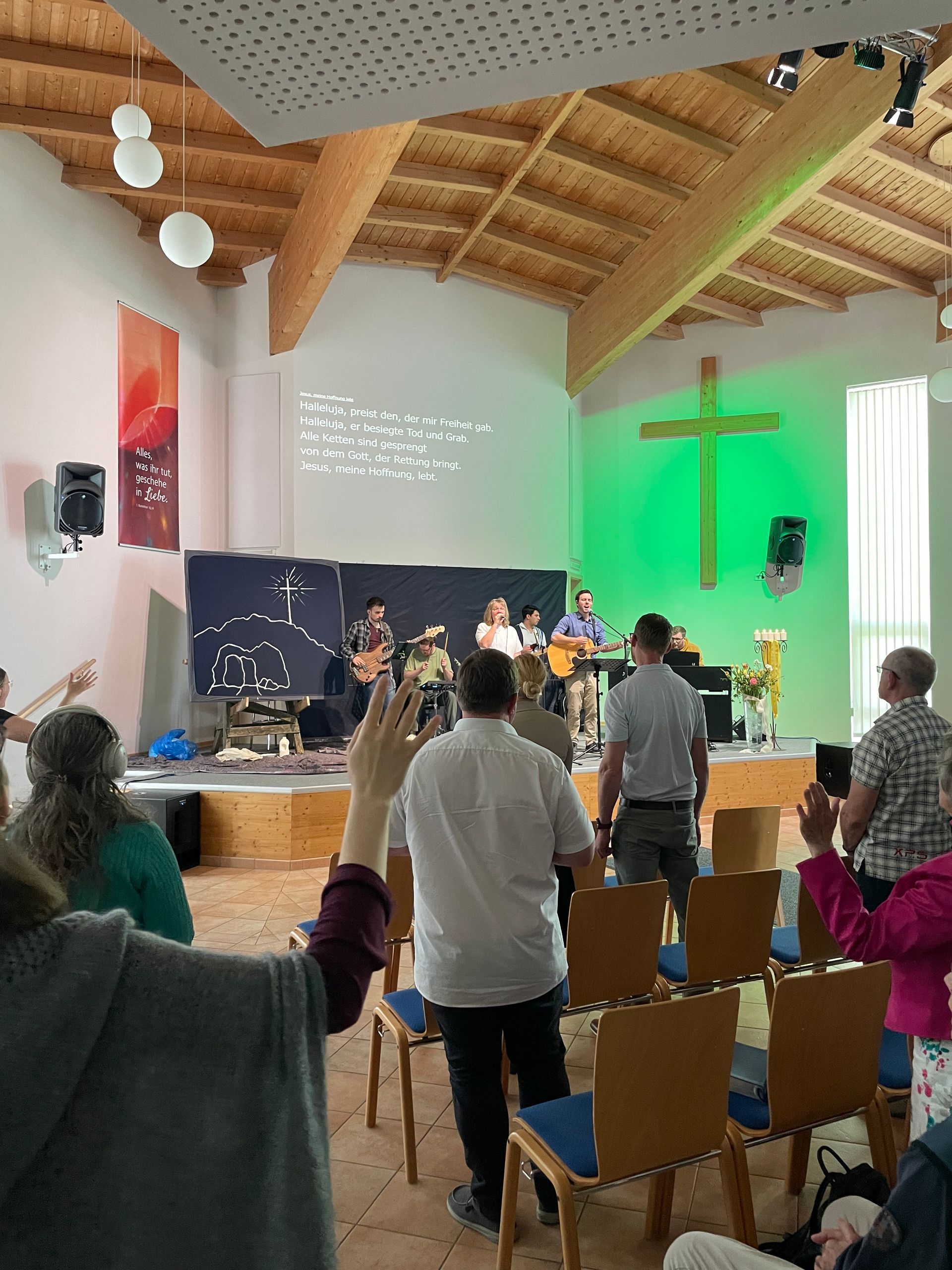Eine Gruppe von Menschen steht in einer Kirche mit einem Kreuz an der Wand