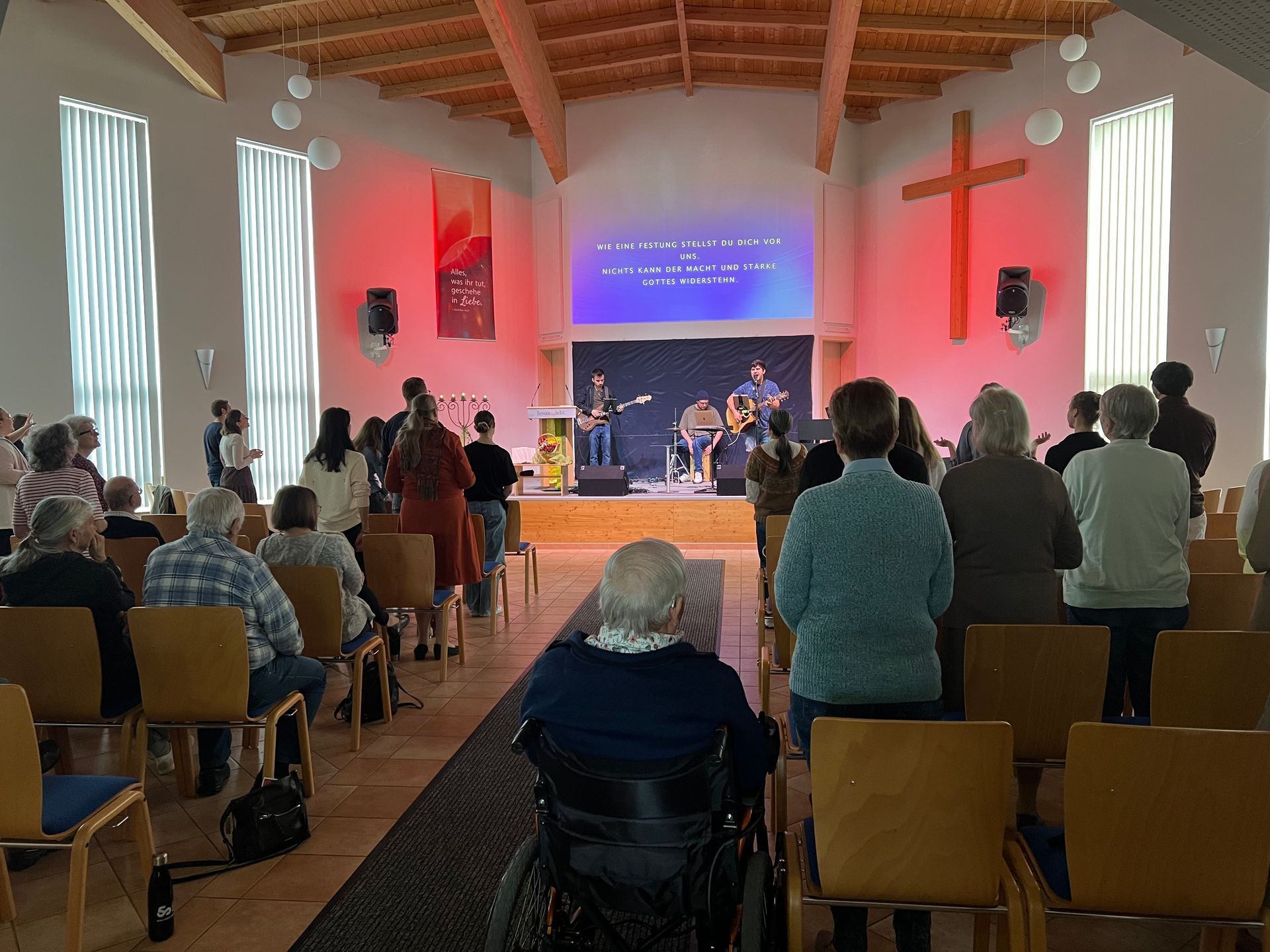 Ein Mann im Rollstuhl sitzt in einer Kirche und sieht sich einen Gottesdienst an.