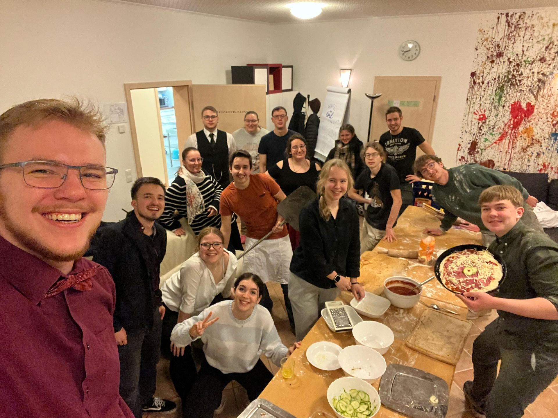 Eine Gruppe von Leuten steht um einen Tisch herum und isst Pizza.