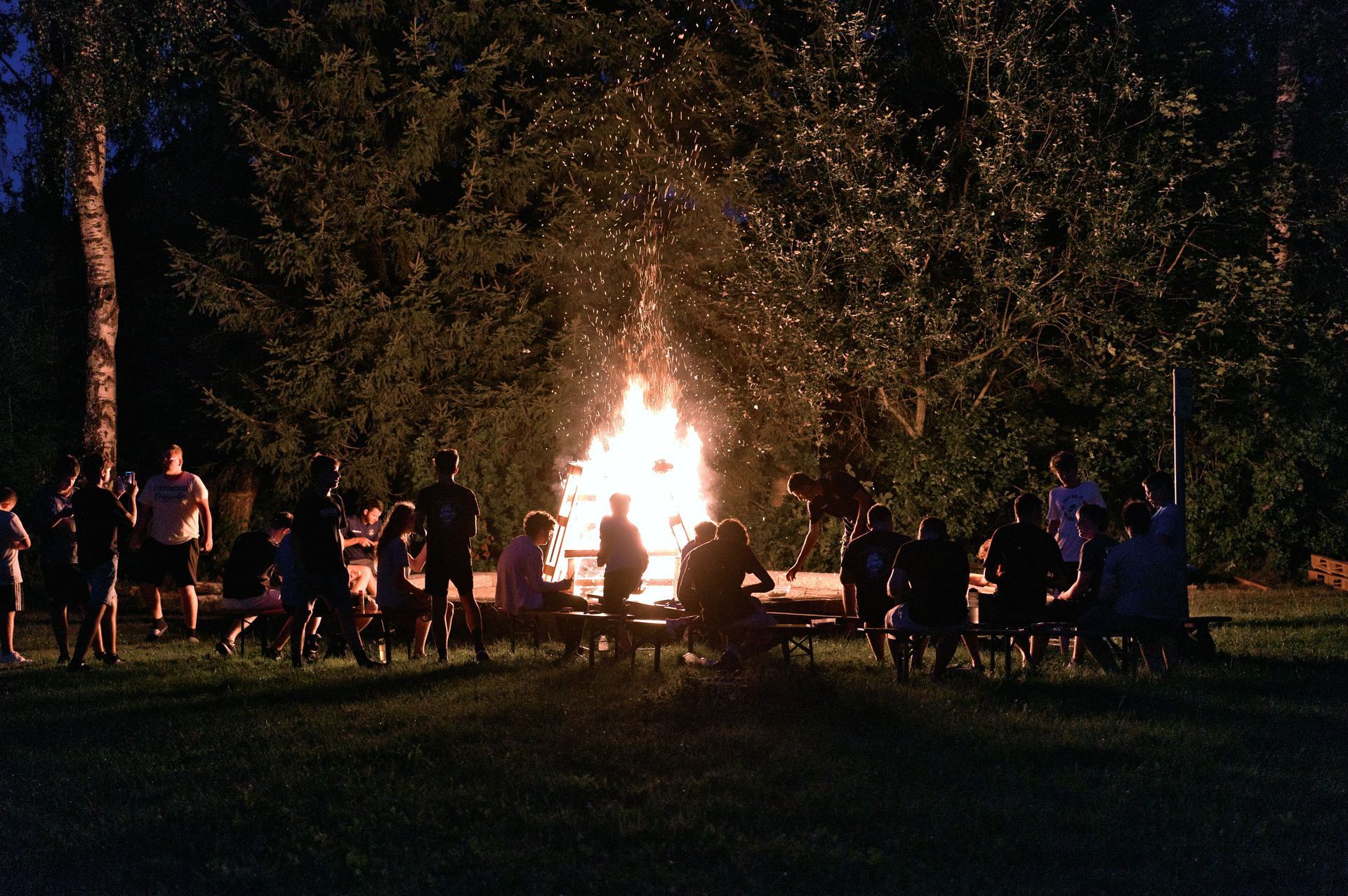 Eine Gruppe von Menschen versammelt sich nachts um ein Lagerfeuer