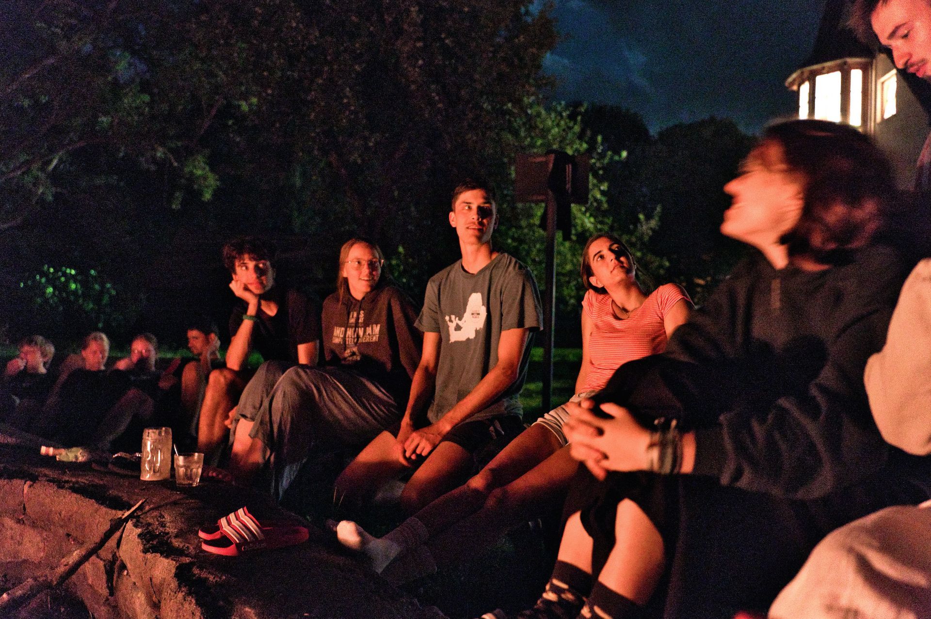 Eine Gruppe von Menschen sitzt nachts um ein Lagerfeuer