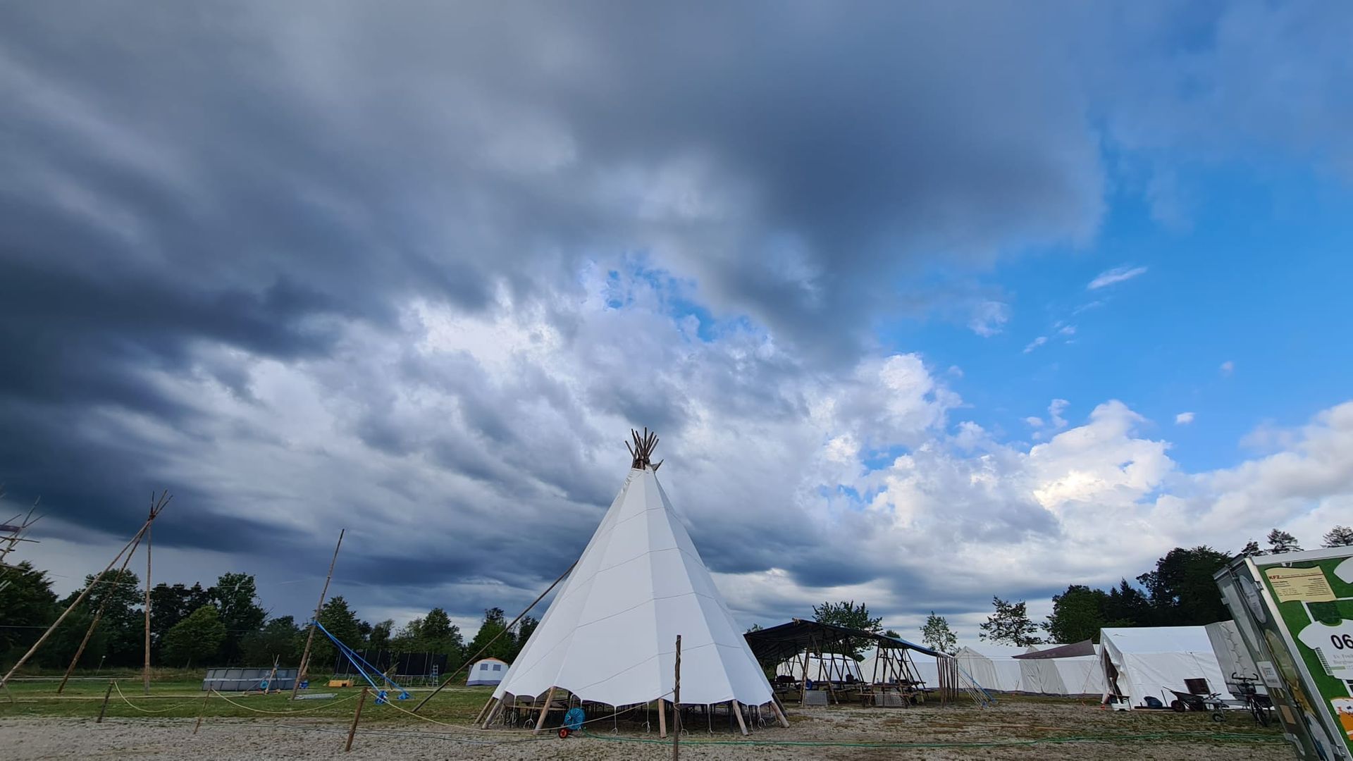 Unter einem bewölkten Himmel steht mitten auf einem Feld ein Tipi.