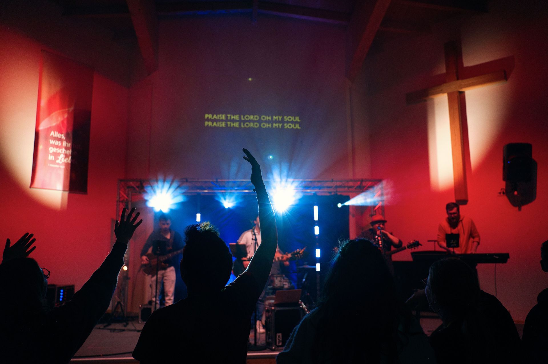 Eine Gruppe von Menschen steht mit erhobenen Händen vor einer Bühne.