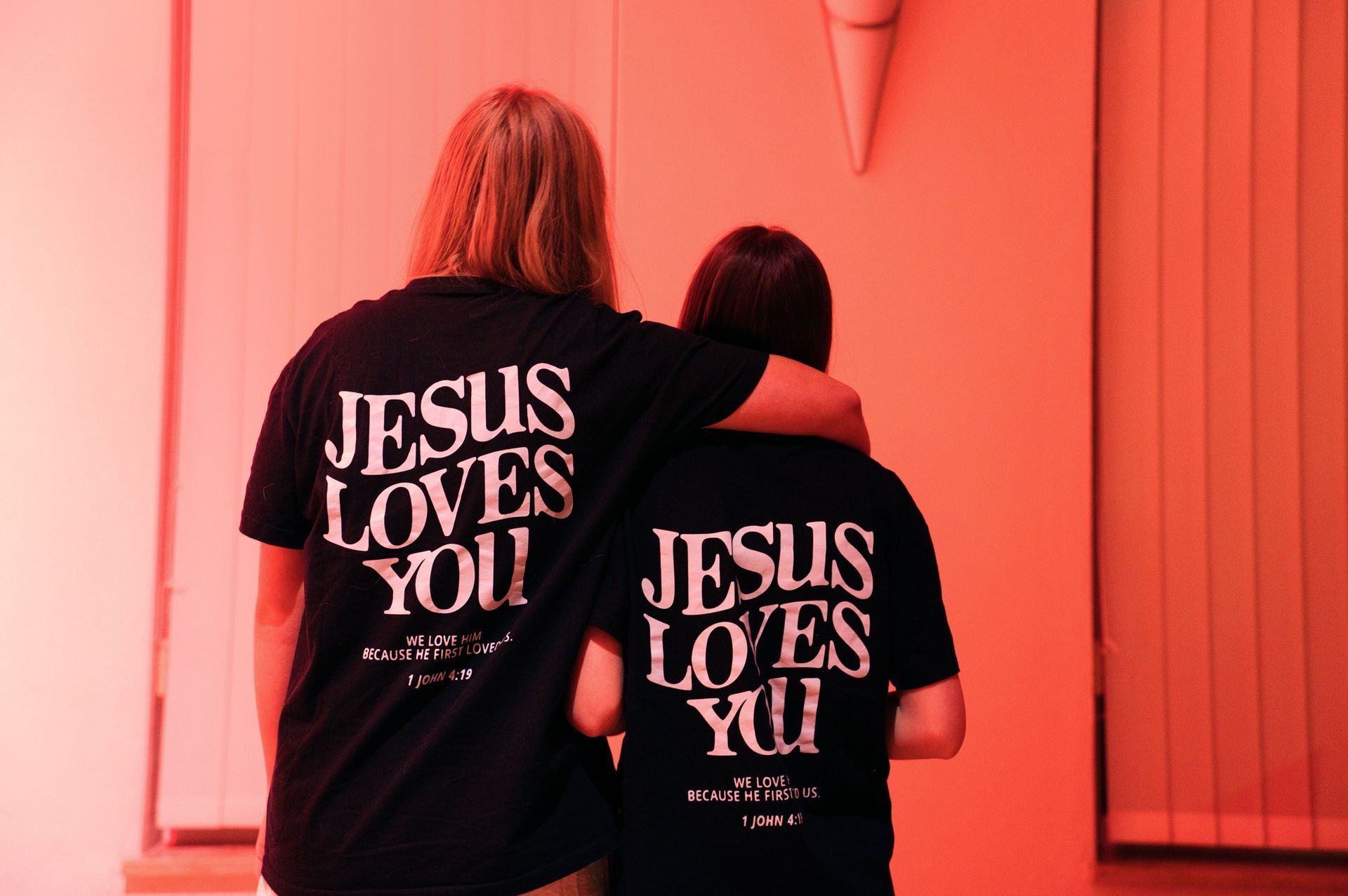 Zwei Menschen, die T-Shirts mit der Aufschrift „Jesus liebt dich“ tragen, stehen nebeneinander.