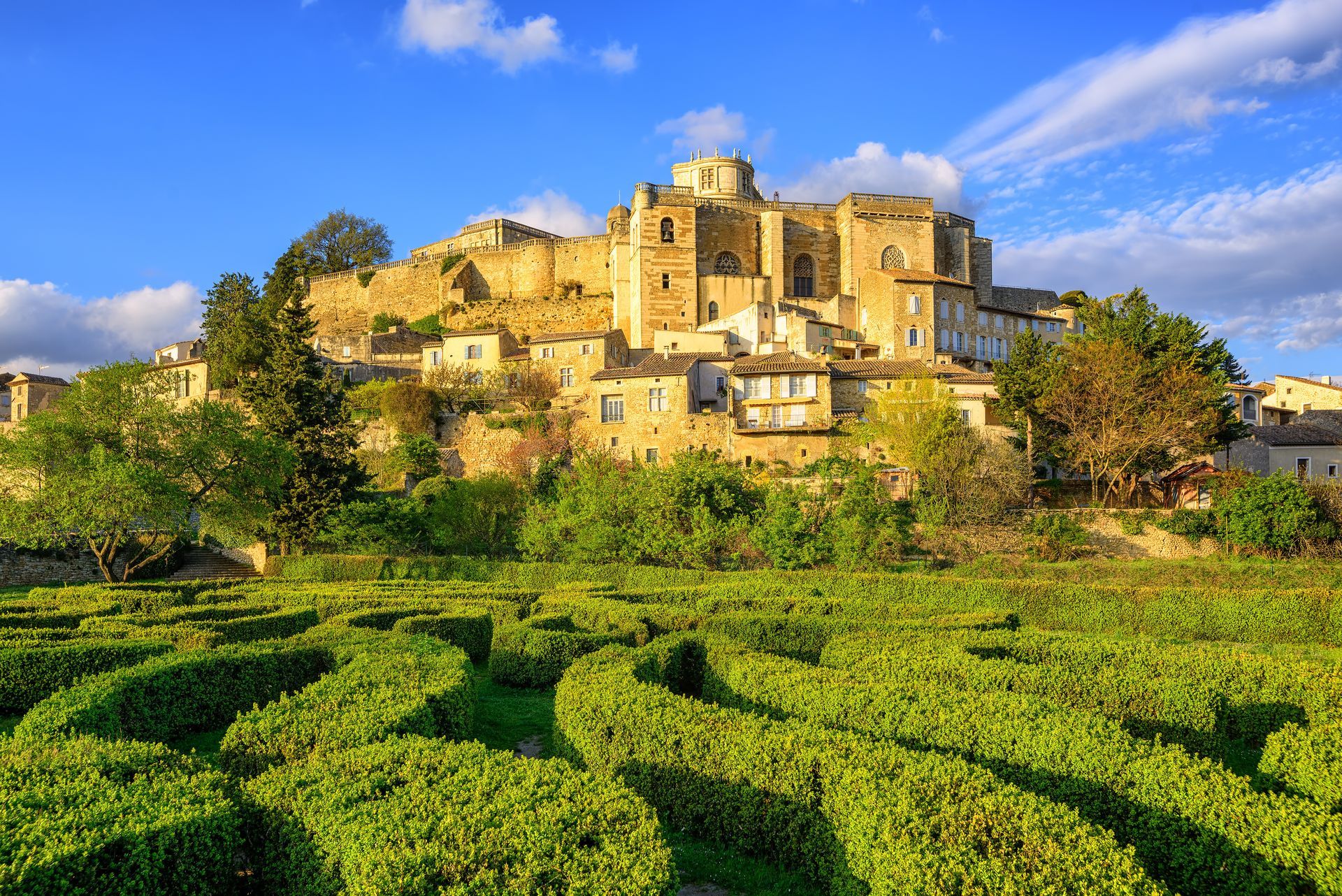 Village ensoleillé perché sur une colline surplombant des vignobles verdoyants sous un ciel bleu