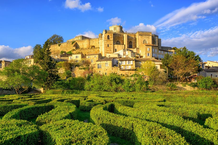 Village ensoleillé perché sur une colline surplombant des vignobles verdoyants sous un ciel bleu