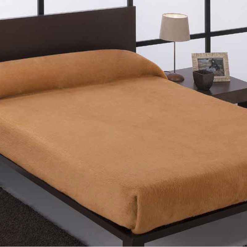 Una cama con un edredón marrón y una lámpara encima.