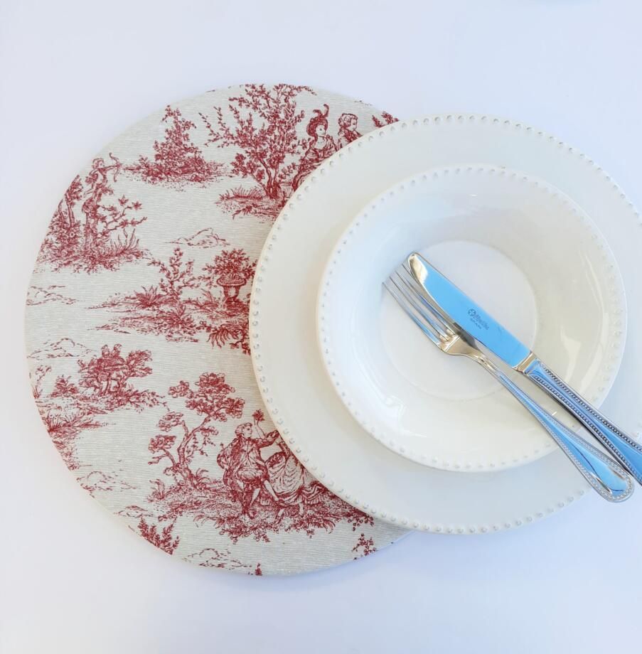 Un mantel individual rojo y blanco con platos y cubiertos encima.