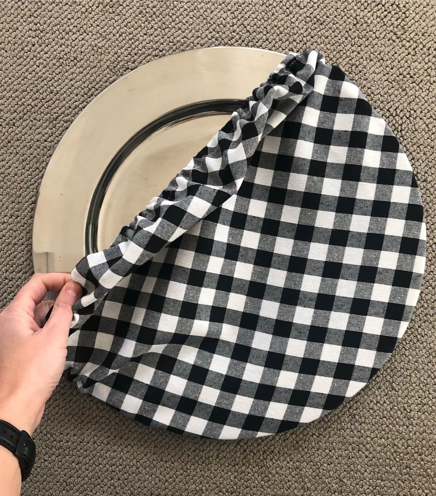 Una persona sostiene una servilleta a cuadros blancos y negros sobre un plato.