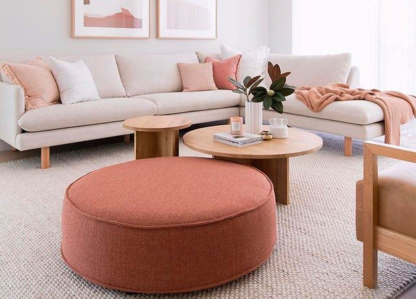 Una sala de estar con sofá, silla, otomana y mesas de café.