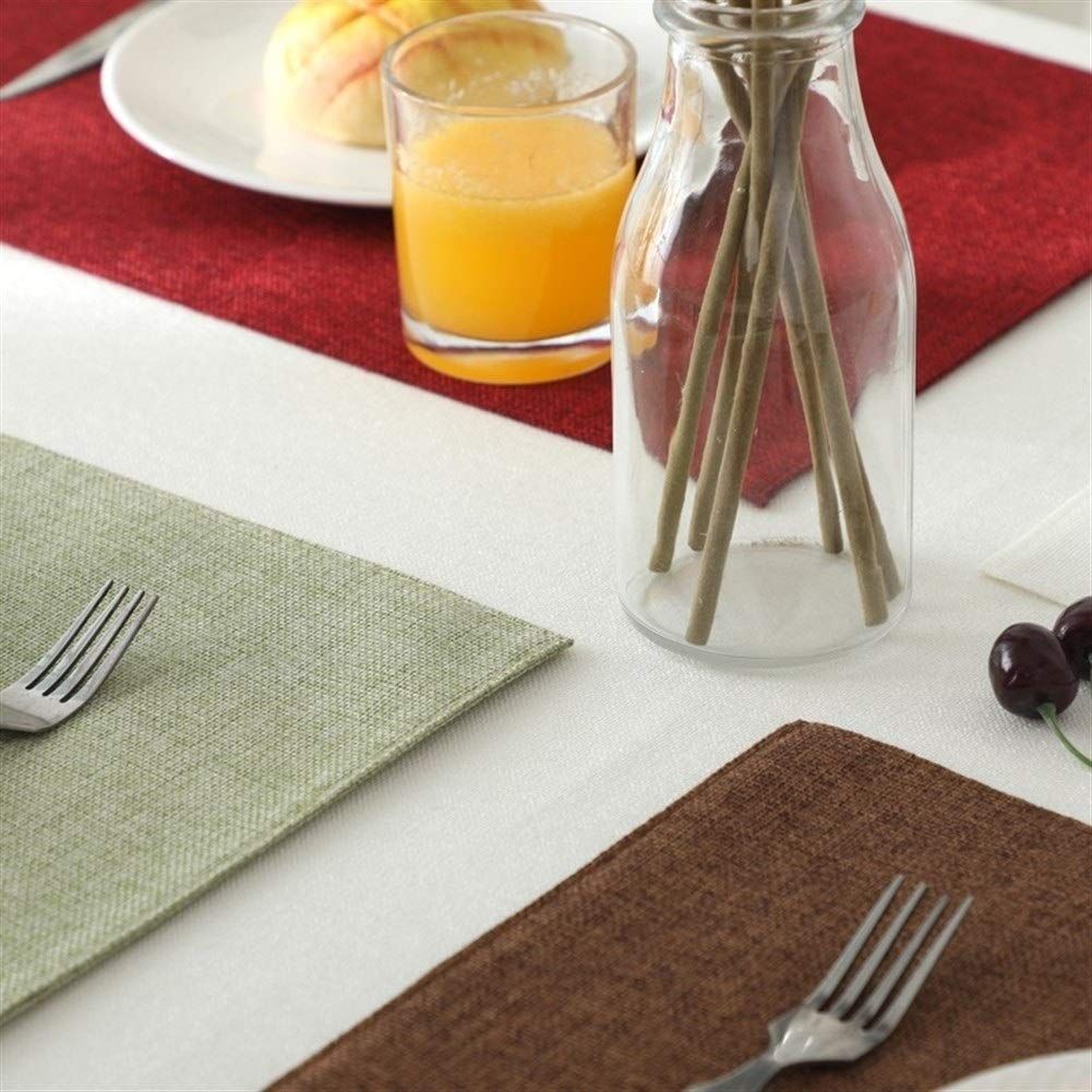 Una botella de pajitas reposa sobre una mesa junto a un vaso de jugo de naranja.