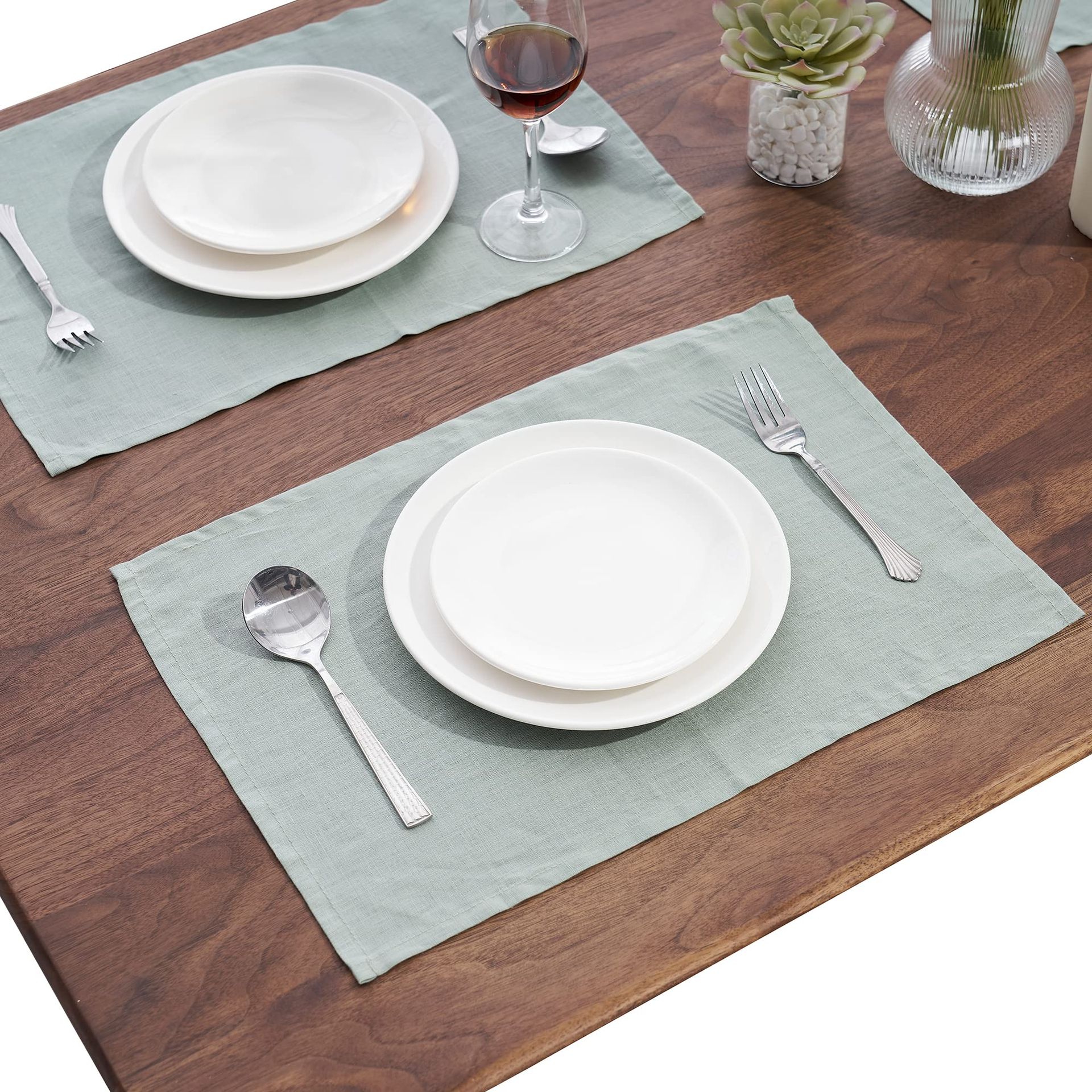 Dos manteles individuales con platos y cubiertos sobre una mesa de madera.