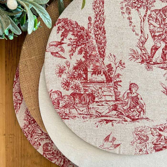 Tres manteles individuales rojos y blancos están apilados uno encima del otro sobre una mesa de madera.