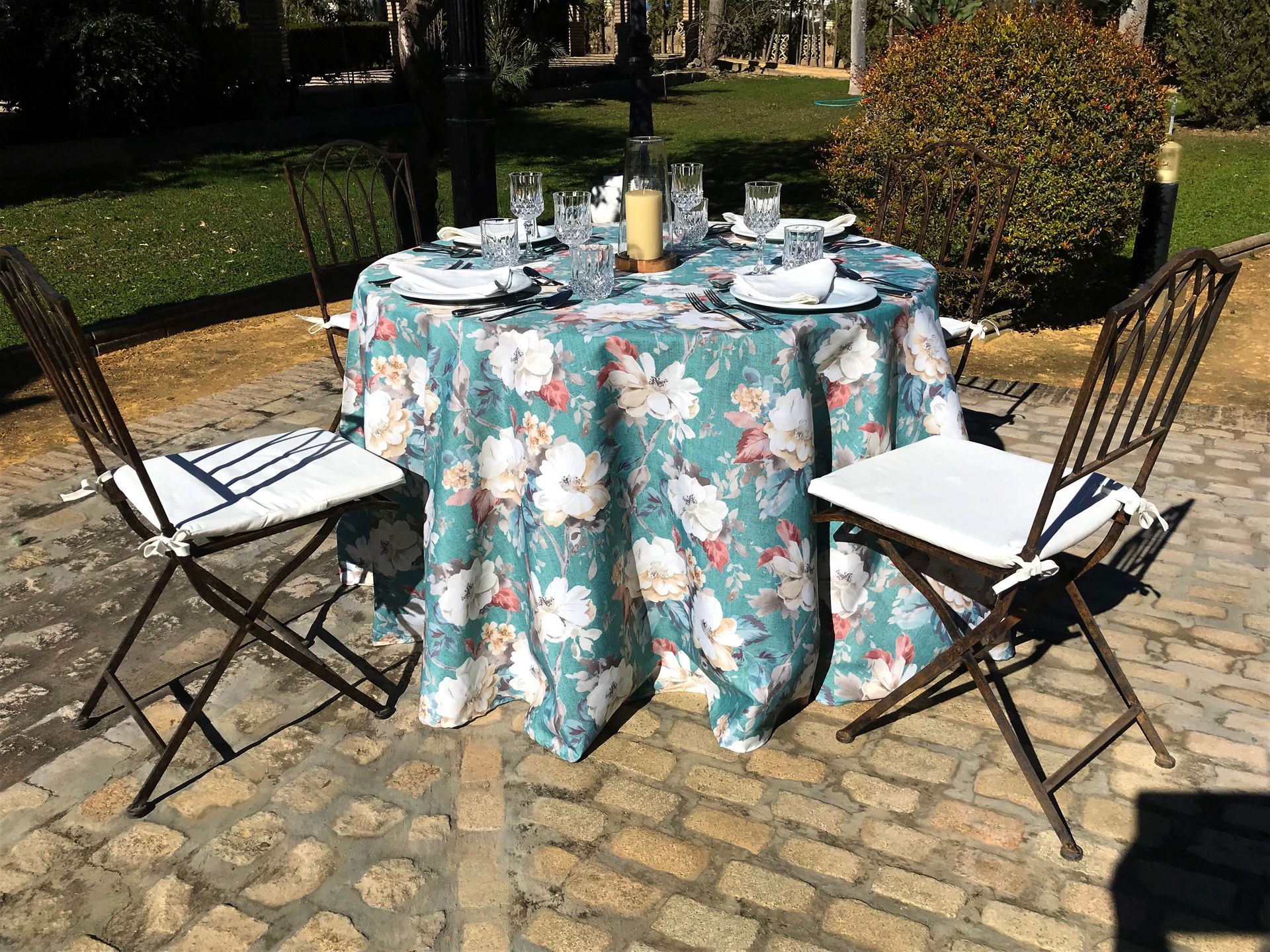 Una mesa con un mantel floral y sillas en un patio de ladrillo.