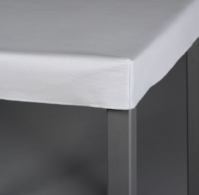 Un mantel blanco está sobre una mesa gris.
