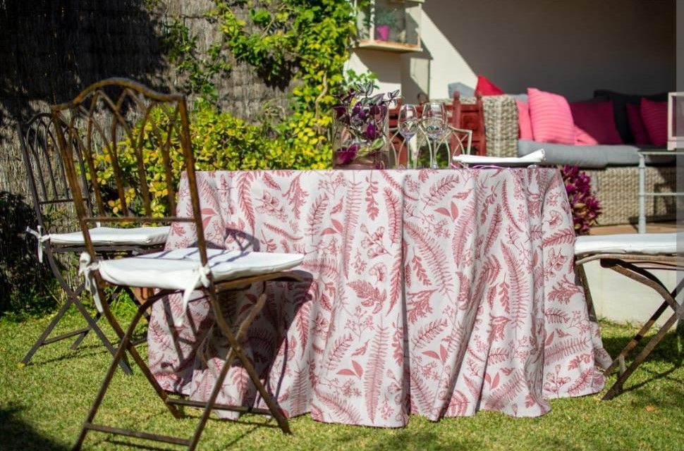 Una mesa con un mantel rosa y sillas en el césped.