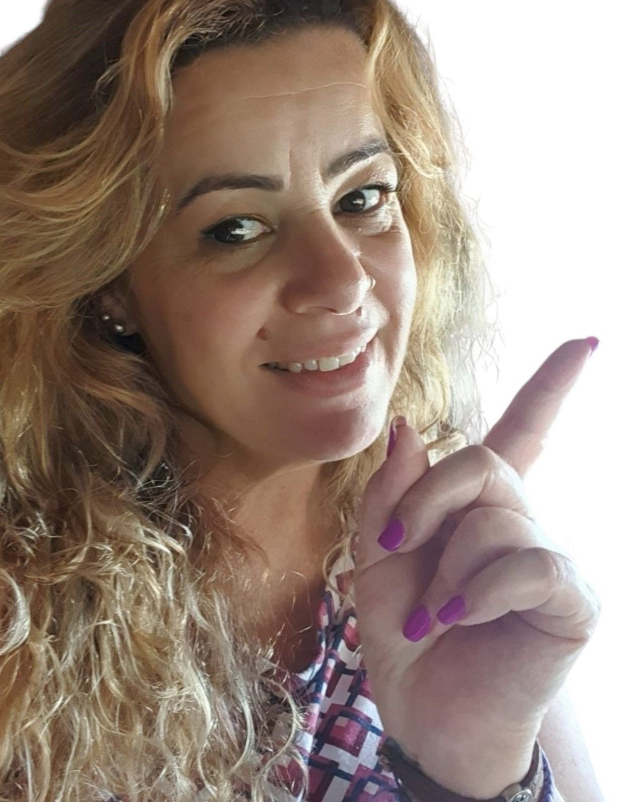 Una mujer sonríe y señala hacia arriba con su dedo.