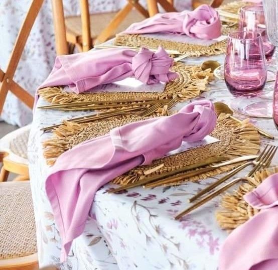 Una mesa con servilletas rosas y cubiertos encima.