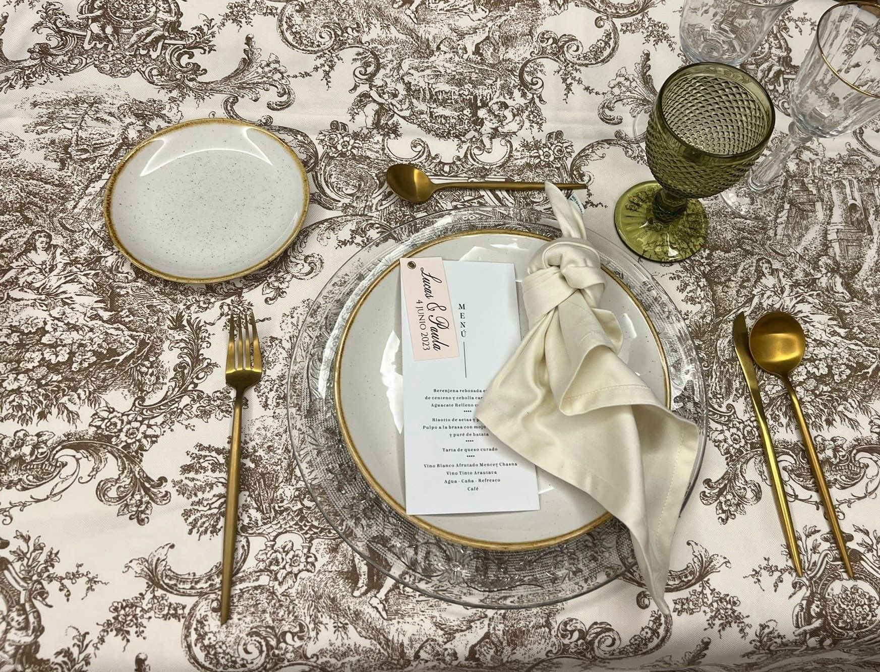 Una mesa puesta con platos, cubiertos, vasos y una servilleta.