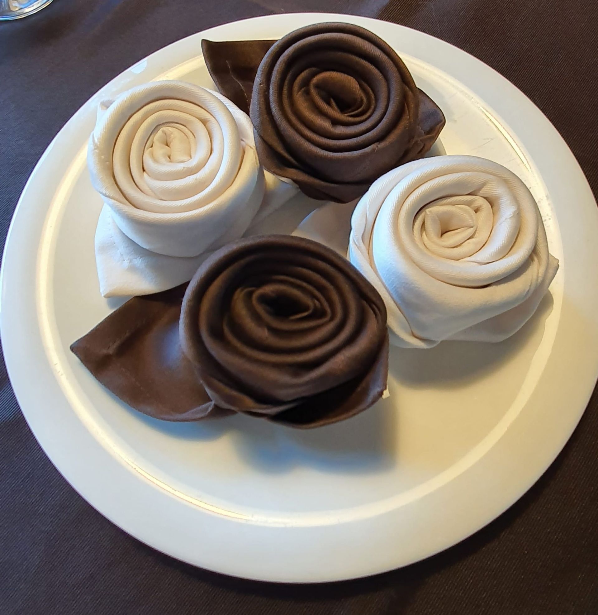 Un plato blanco con cuatro rosas marrones y blancas encima.