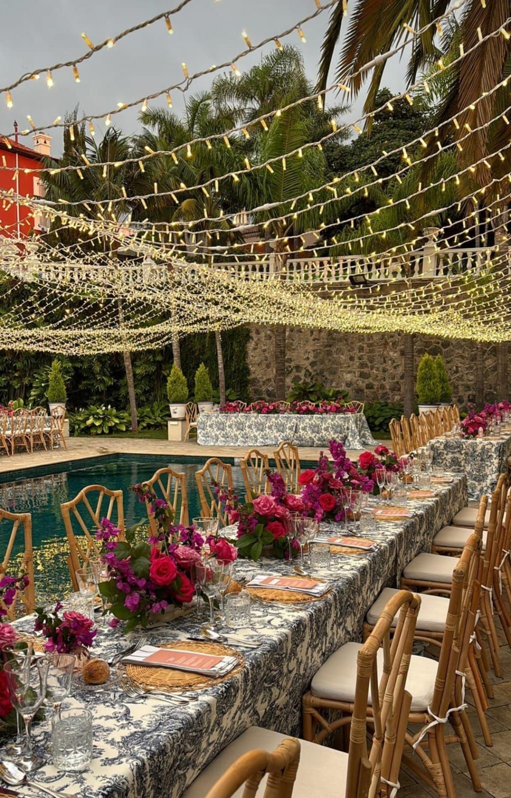 Una mesa larga con flores está situada junto a una piscina.