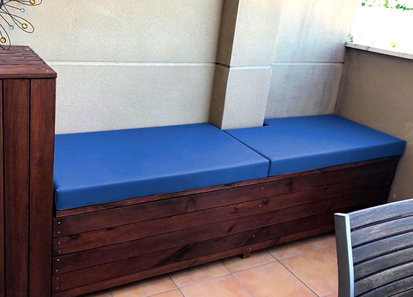 Un banco de madera con cojines azules en un balcón.