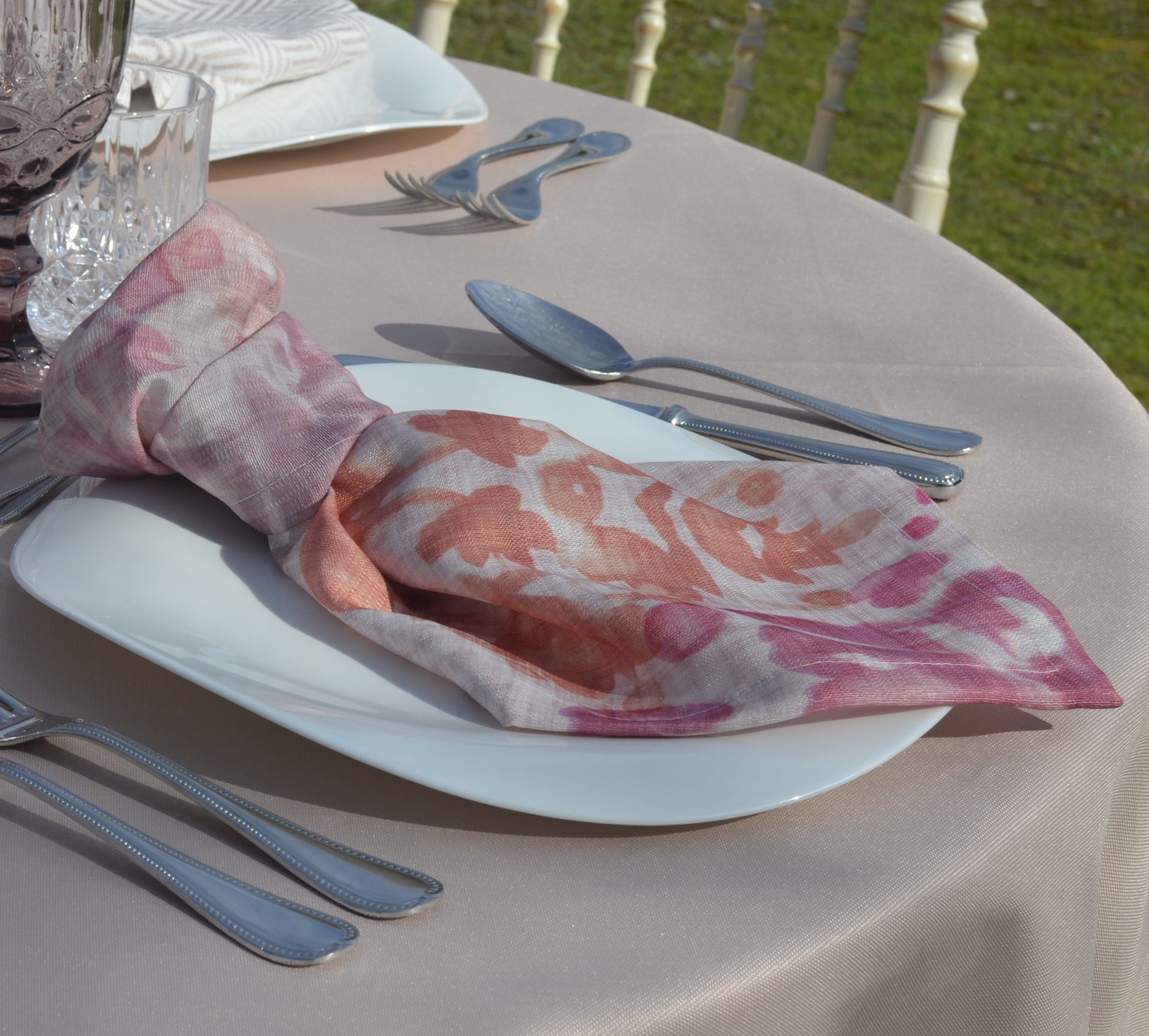 Un plato blanco con una servilleta rosa encima.