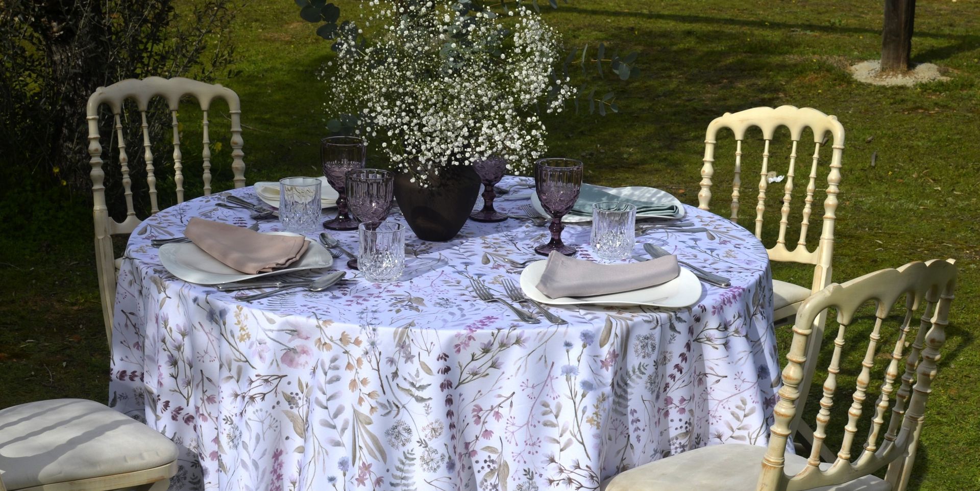 Una mesa redonda preparada para comer en un jardín con césped