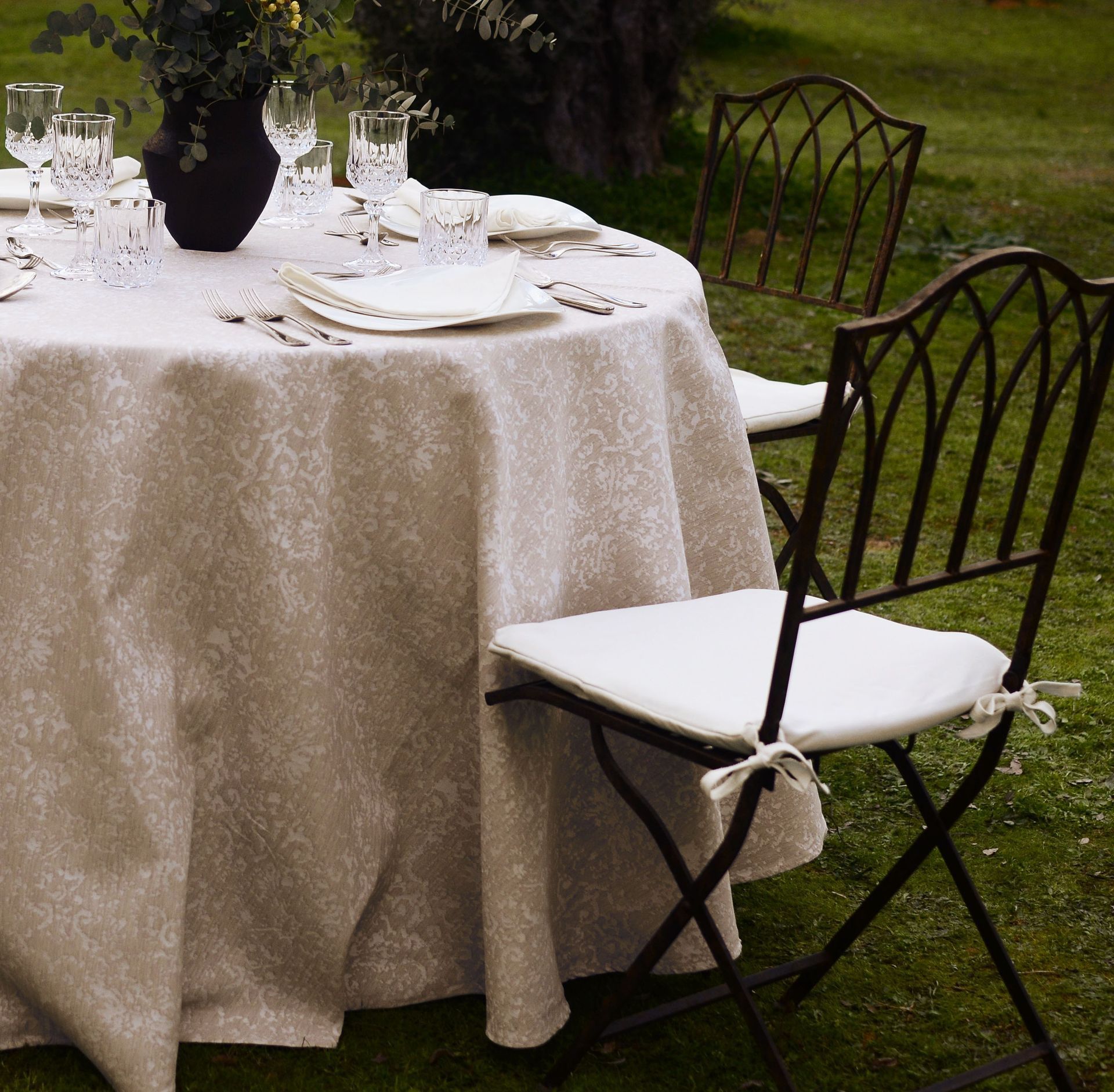 Una mesa con un mantel blanco y un jarrón de flores encima.