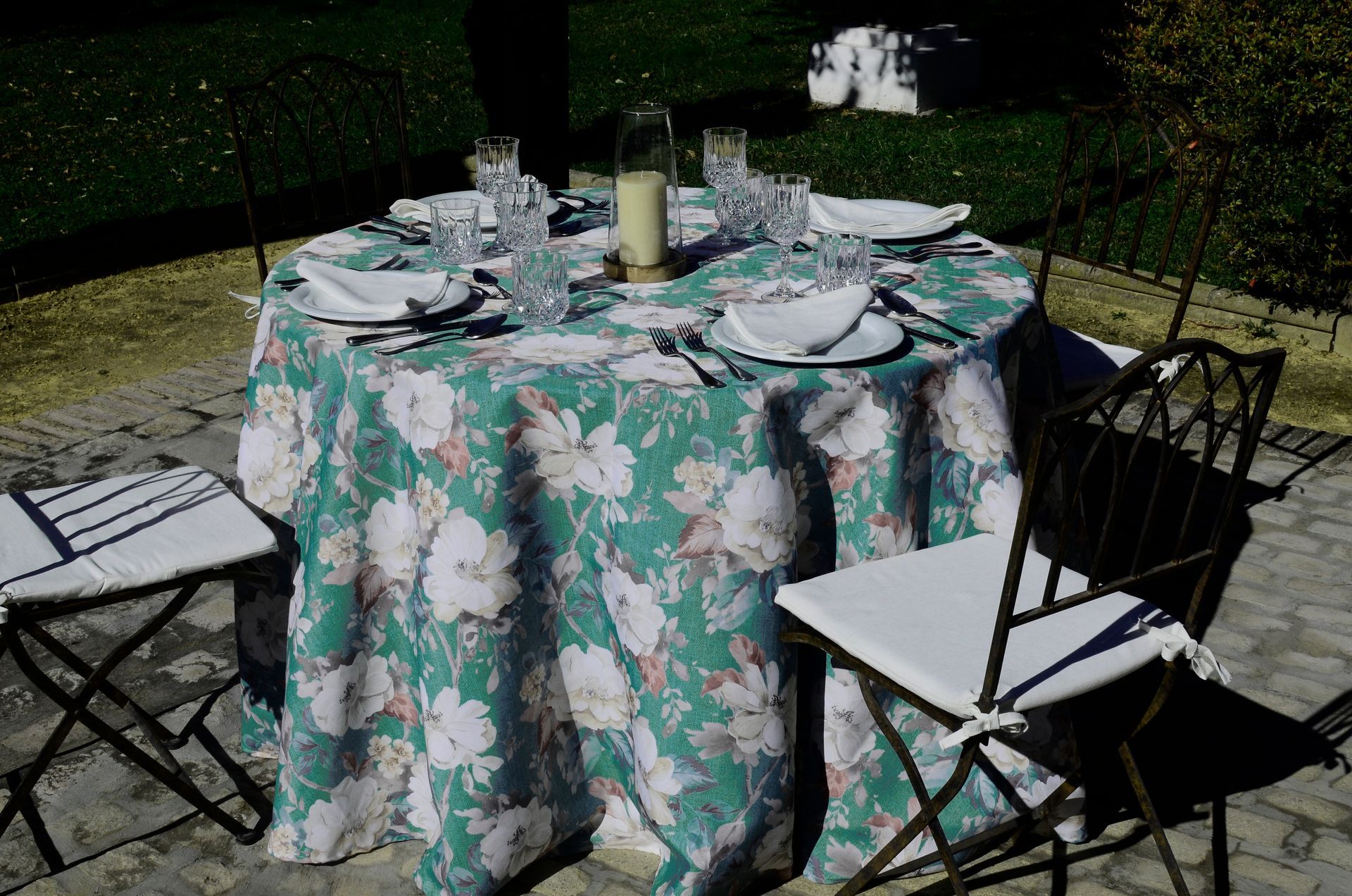 Una mesa redonda con un mantel floral y sillas.