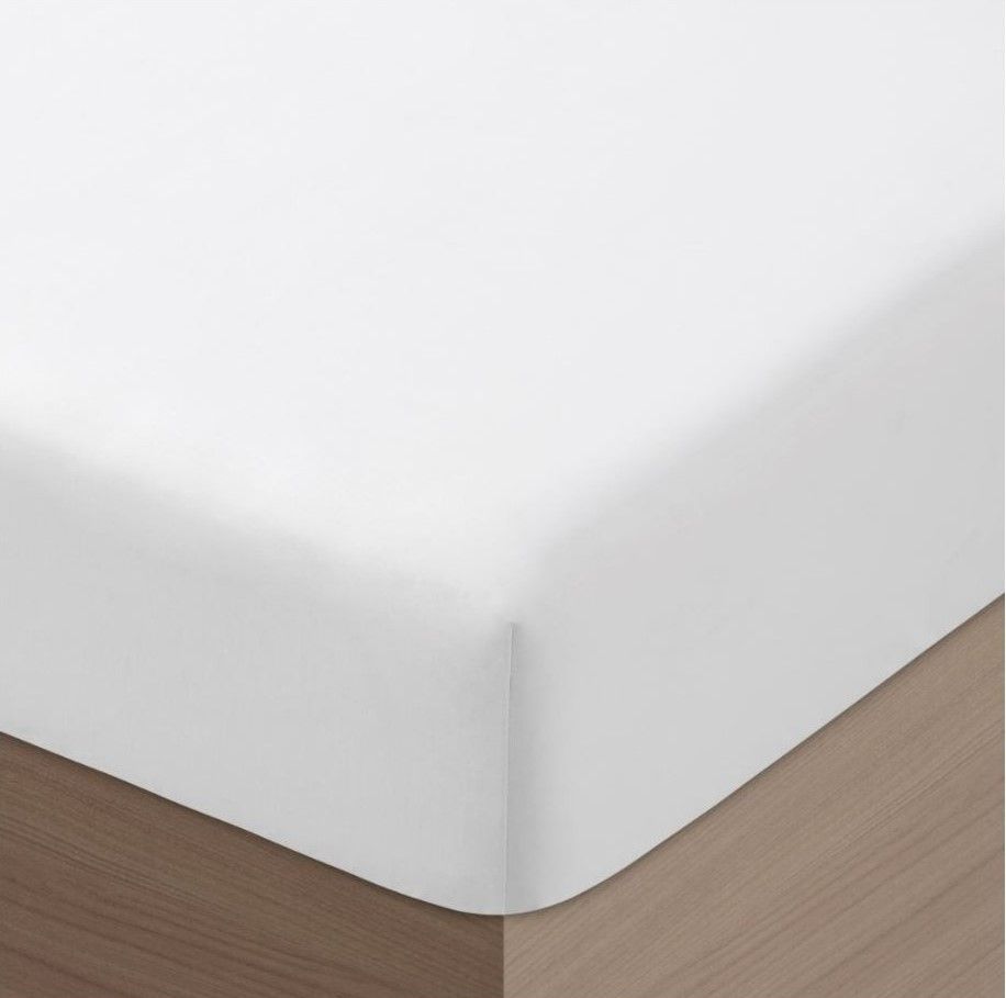 Una colcha blanca está encima de una cama de madera.