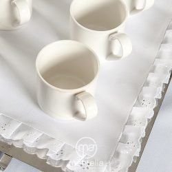 Tres tazas de café blanco están sobre una bandeja blanca.