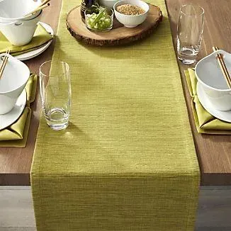 Una mesa con cuencos, vasos, palillos y un camino de mesa.