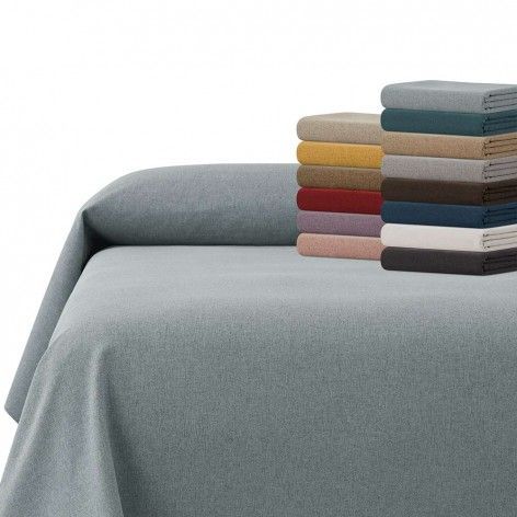 Cama con funda de color azul claro y una pila de mantas dobladas en varios colores.