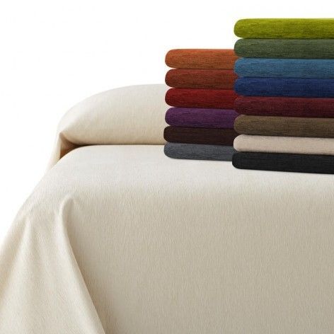Cubrecama de color crema con una pila de mantas de colores en varios colores: verde, azul, rojo, etc.