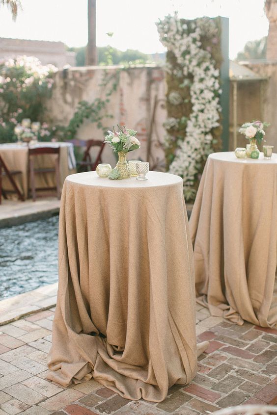 Un par de mesas con mantelería están junto a una piscina.