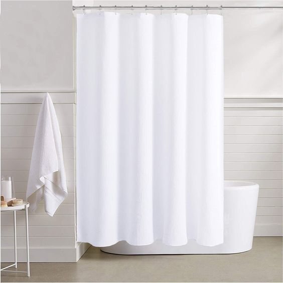 Una cortina de ducha blanca cuelga sobre una bañera en un baño.