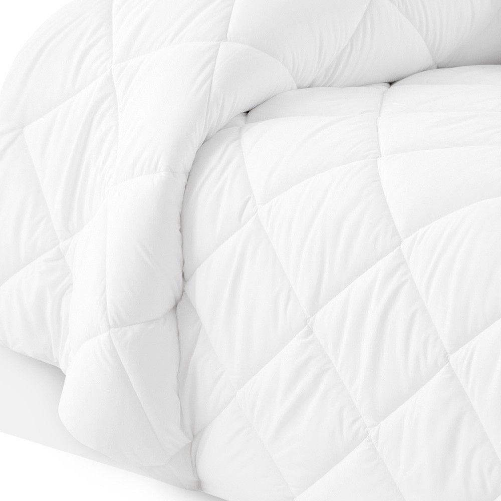 Un primer plano de un edredón blanco sobre una cama.